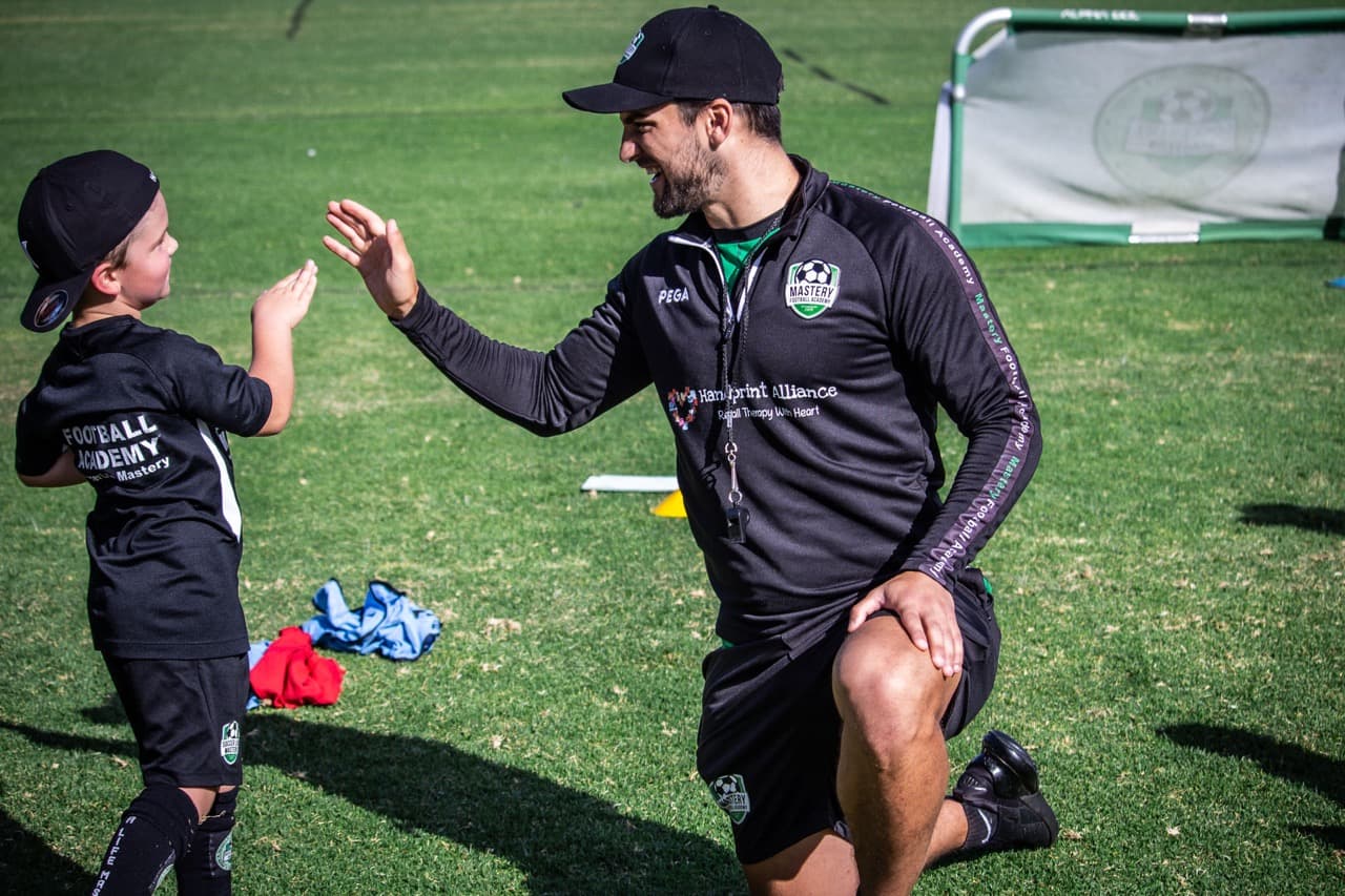 A football coach encouraging a young player during a Mastery session in Adelaide